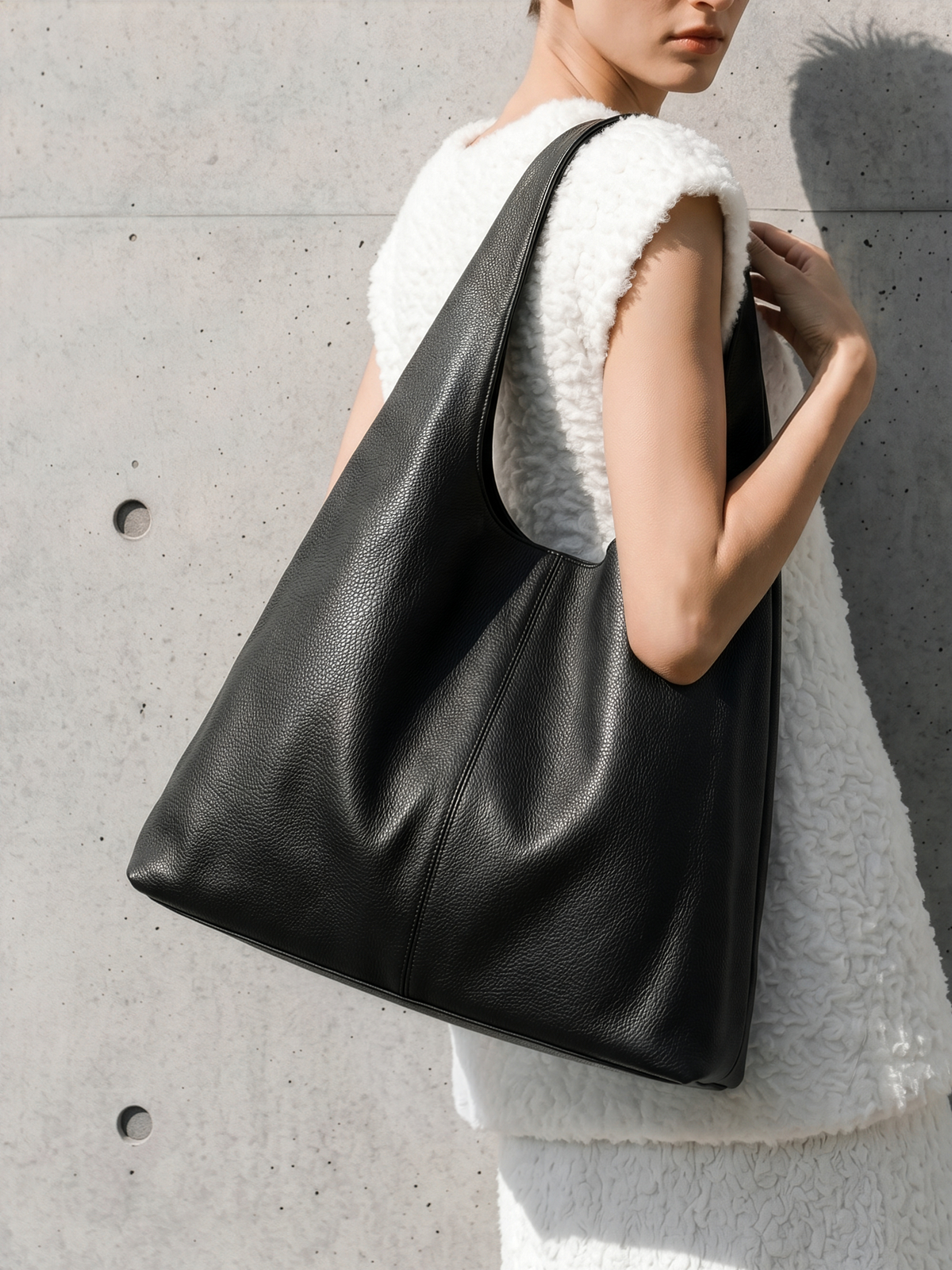 Woman in a white shearling vest carrying The Anse in Noir on her shoulder