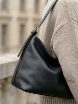 The Houle Petite in Noir worn on the shoulder over a beige sweater on a city street