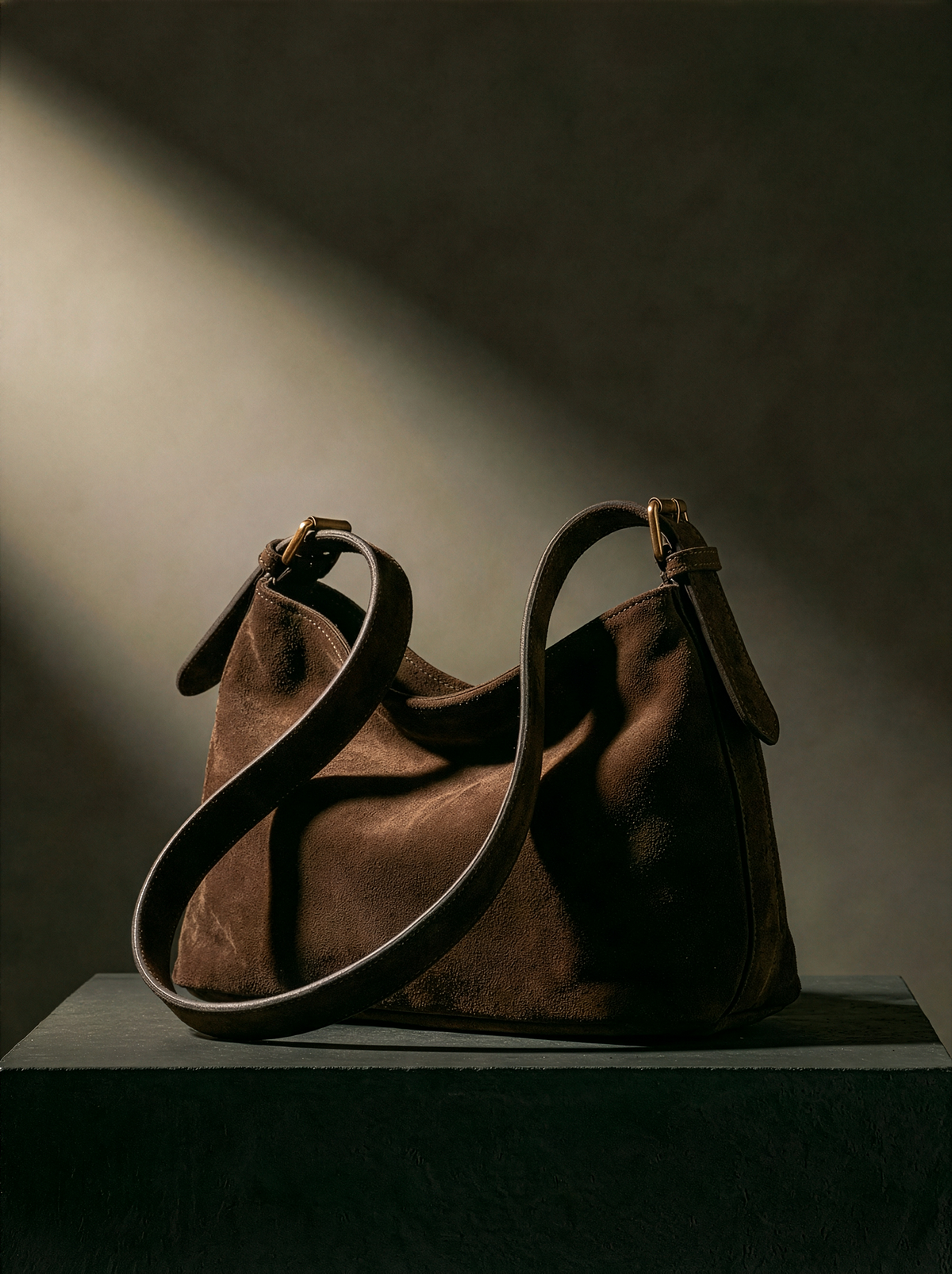The Houle Petite Suede in Chocolate on a stone plinth in soft light