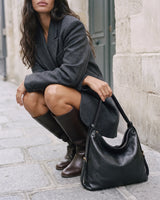 The Jusant Carryall in Noir beside her on the cobblestones